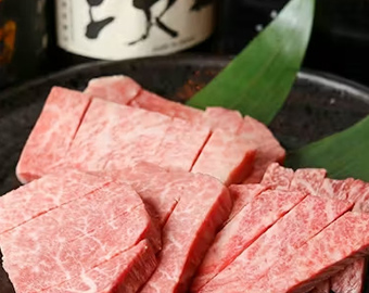 日本酒の瓶を背景にした霜降り和牛の盛り付けの写真