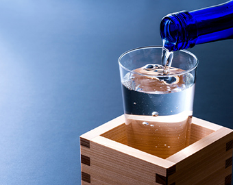 青いボトルからグラスに日本酒を注ぐ様子の写真